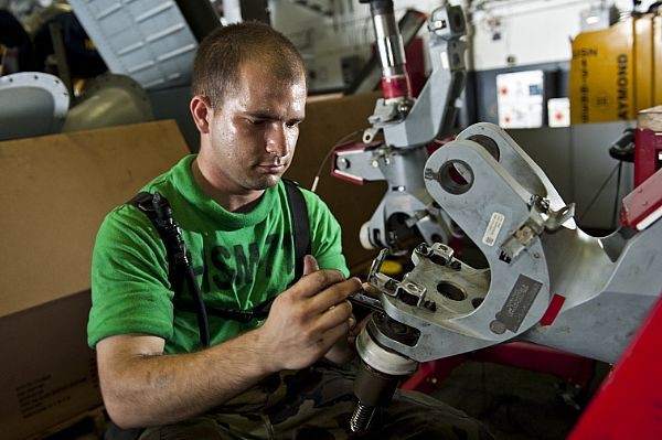 Một thợ kỹ thuật đang sửa chữa một chi tiết máy liên quan đến trục quay của trực thăng MH-60R Sea Hawk, thuộc biên chế của một phi đội trực thăng khác cũng thuộc biên chế của tàu sân bay USS John C. Stennis (ảnh ngày 31/8/2011).